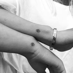 two girls with matching tattoos on their arms holding each other's hands and looking at the camera