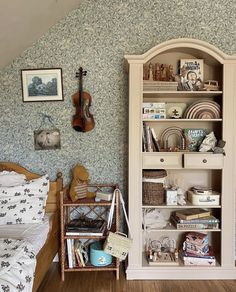 a bed room with a book shelf and a guitar on the wall next to it