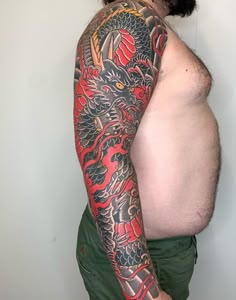 a man with a dragon tattoo on his arm and half - sleeved shirt is standing in front of a white wall