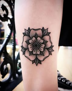 a black and white flower tattoo on the right side of the leg, with an arrow in the center