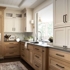 a kitchen filled with lots of wooden cabinets and counter top space next to a window