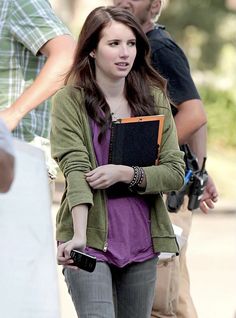 a woman walking down the street while holding a book