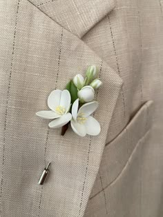 a boutonniere with white flowers pinned to the lapel of a suit