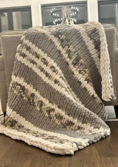 a gray and white blanket sitting on top of a couch