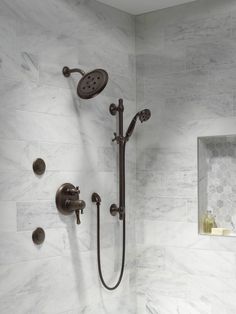 a bathroom with marble walls and flooring, including a shower head and hand shower faucet