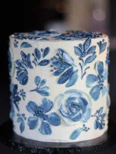 a blue and white decorated cake sitting on top of a black table with frosting