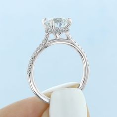 a close up of a person's hand holding an engagement ring