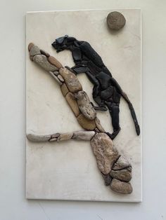 an animal made out of rocks on top of a white wall