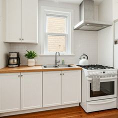 a kitchen with white cabinets and an oven in the corner, next to a window