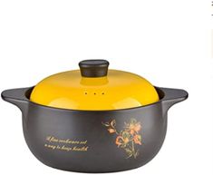 a yellow and black casserole with flowers painted on the side, sitting in front of a white background