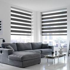 a living room filled with furniture and windows covered in roman blind shades on the windows