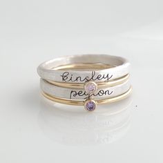 Cursive Name Stackable Birthstone Ring Set This set includes four rings! You will receive two name rings in fine silver (.999) engraved in our cursive font. These tarnish much slower than sterling silver since they have less copper. You will also receive two skinny cz birthstone rings in 14K yellow gold filled. These rings are handmade in our Indiana studio. Each engraved ring starts from a spool of wire. They are handcut, handformed and soldered in the first process of creating your ring. They Name Rings Personalized, Personalized Mom Jewelry, Stackable Name Rings, Mothers Rings, Stackable Birthstone Rings, Birthstone Stacking Rings, Rings Personalized, Mothers Ring, Mother's Day Jewelry