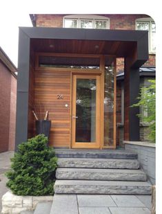 the front door of a house with steps leading up to it and a planter on the side