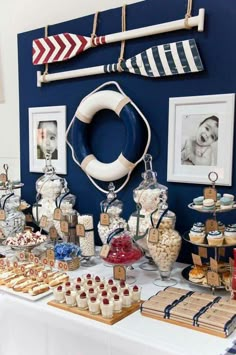 a table topped with lots of desserts and candies next to a blue wall