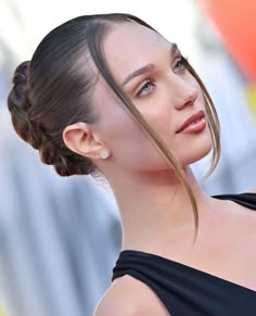 a woman wearing a black dress with a braid in her hair is looking off to the side