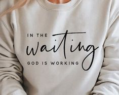 a woman wearing a sweatshirt that says in the waiting god is working