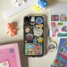 an assortment of cute stickers and magnets on a white surface next to a cell phone