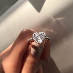 a woman's hand with a diamond ring on top of her finger, in front of a white background