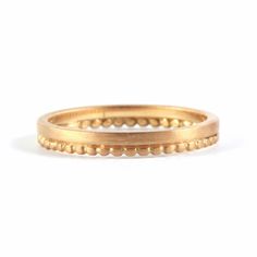 a gold ring with beading on the outside and inside, set against a white background