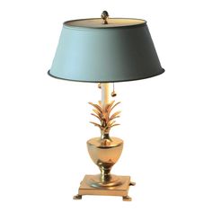 a gold pineapple lamp on a wooden base with a light blue lampshade