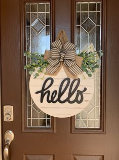 a wooden door with a wreath and bow on it that says hello, hells