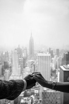 two people reaching out their hands to each other in front of a cityscape