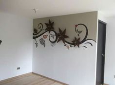 an empty room with white walls and decorative metal art on the wall, along with wooden floors