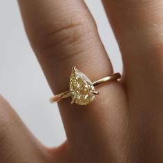 a woman's hand with a yellow diamond ring on her left thumb and the tip of her finger