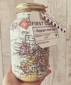 a hand holding a mason jar with a map on it and a tag that says first class