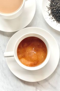 there is a cup of tea on the table next to another cup and saucer