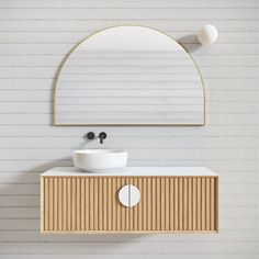 a white sink sitting under a mirror on top of a wooden cabinet next to a wall