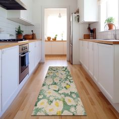 a kitchen with wooden floors and white cabinets, along with an area rug on the floor