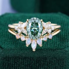 a ring with an oval cut green and white diamond surrounded by smaller pear shaped diamonds