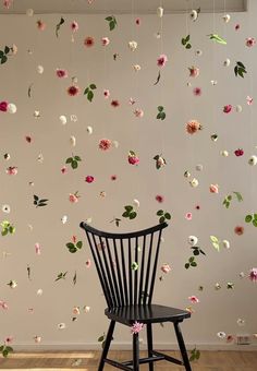 a chair sitting in front of a wall with flowers hanging from it's sides