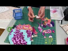 a person cutting up flowers on a table with scissors and other crafting supplies in the background