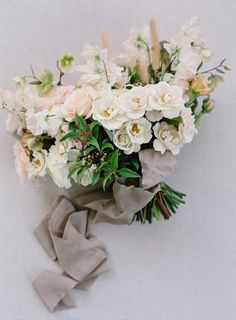 a bouquet of white and pink flowers on a gray cloth tied to a tablecloth