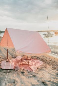 a pink tent sitting on top of a sandy beach