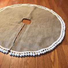 a round piece of cloth with holes in the middle on a wooden floor next to a pair of scissors