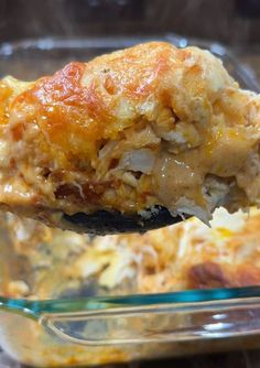 a spoon full of casserole with meat and cheese on it is being lifted from the casserole dish