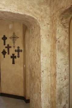 an arched hallway with crosses on the wall