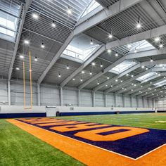 an indoor sports facility with artificial turf and lights