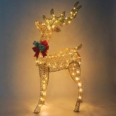 a lighted reindeer with a red bow on its antlers is standing in front of a white background