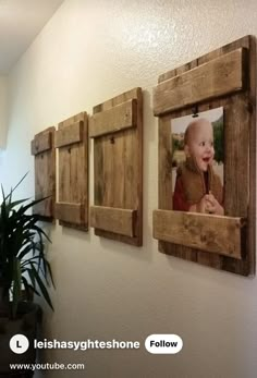 three wooden frames hanging on the wall with a baby's picture in them and a potted plant next to it