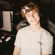 a young man sitting in front of a computer desk with headphones on his ears