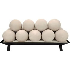 a bunch of white balls sitting on top of a black stand in front of a white background