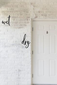 a white brick wall with the words wet dry written on it and an open door