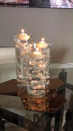 two vases filled with rocks and candles on top of a table in front of a mirror