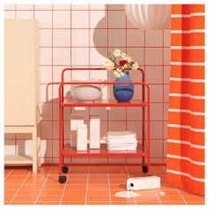 a red cart with plates and bowls on it in a bathroom next to a shower curtain