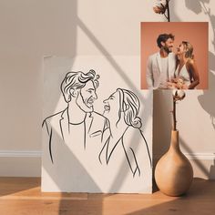 a couple is drawn on a piece of paper next to a vase with flowers