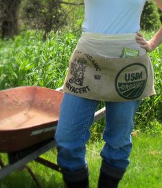 a woman standing next to a wheelbarrow with a bag on it's back